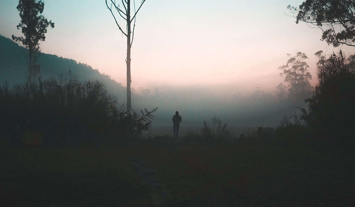 a man standing in a valley at sunrise