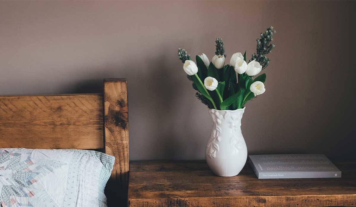 white flowers in a vase on a bedside table